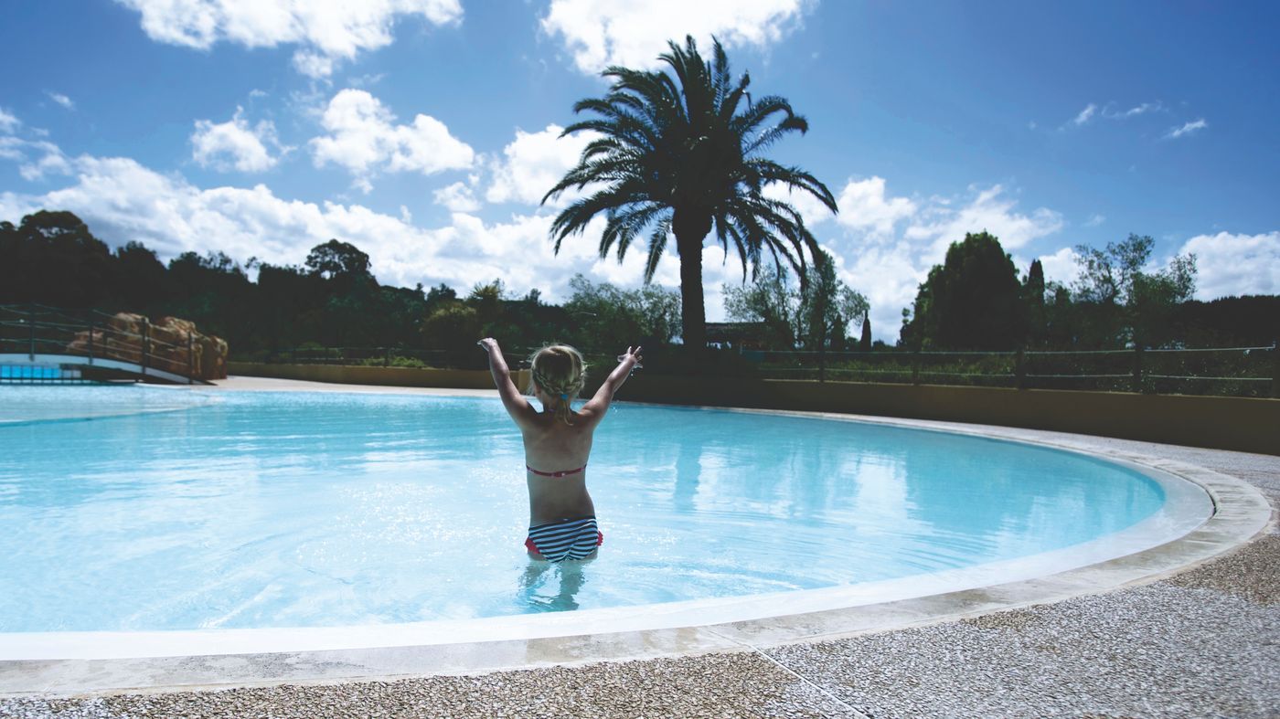 Jeune fille dans une piscine de village de vacances par une journée d'été